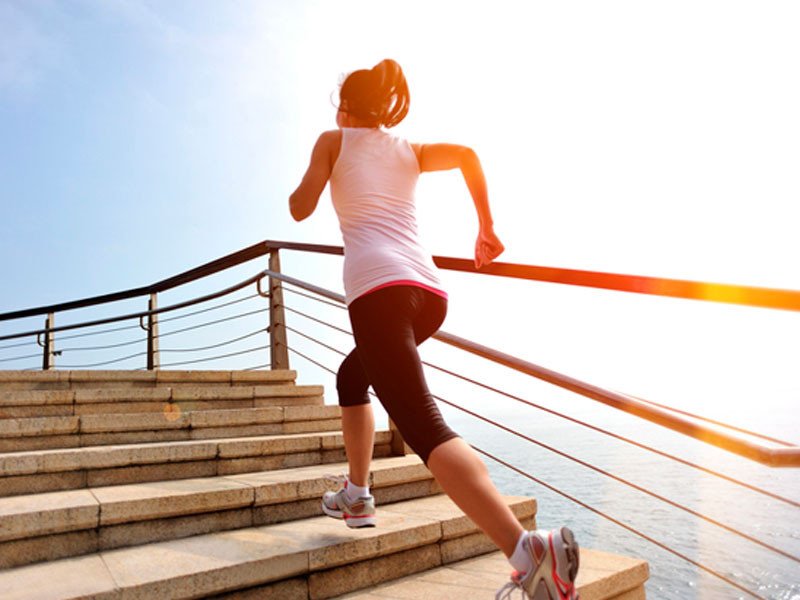 Life Extension, a slim woman is running and stair climbing on warm, sunny day next to the sea or ocean